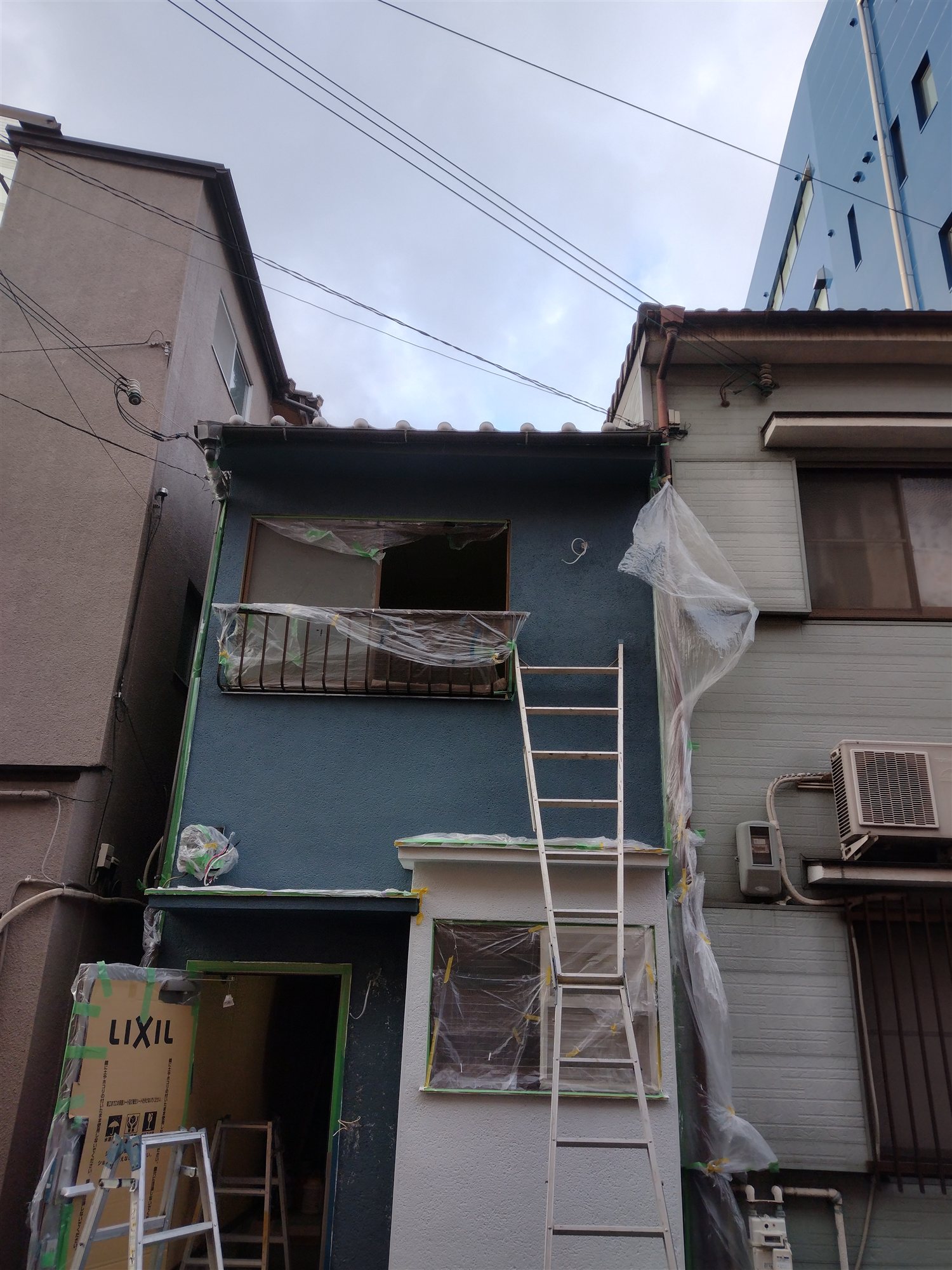 千代崎①の施工中の外観。外壁の塗装作業中で養生シートが張られている