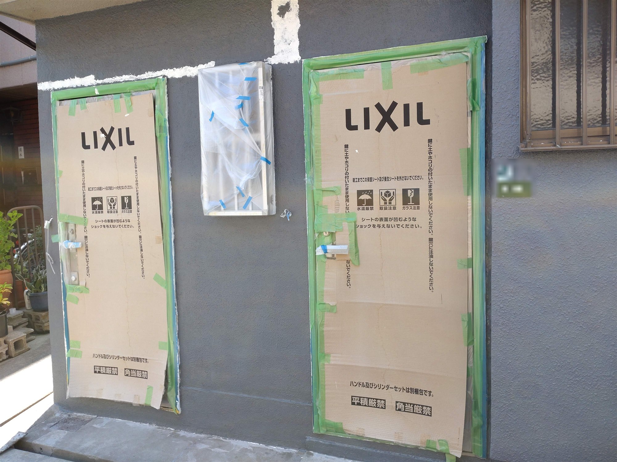 西九条アパートの施工中の外観。新しい玄関ドアが養生された状態で設置されている